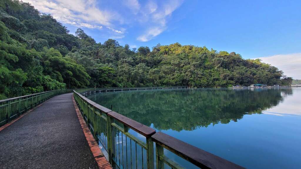 Blue sky, white clouds and green trees reflected on the lake